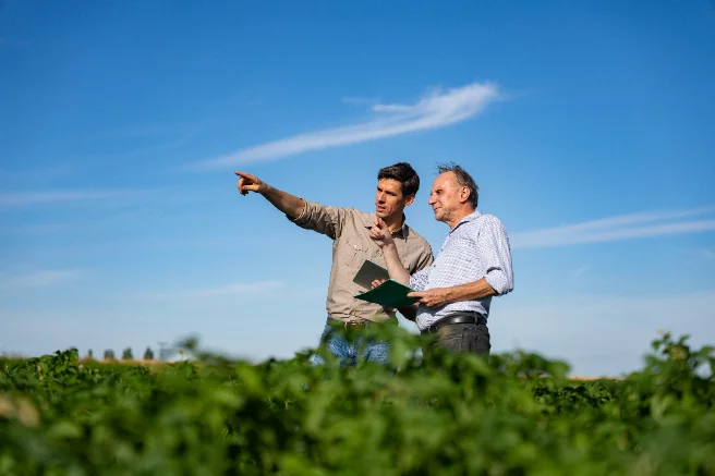 An Adapter and a grower talking in a field